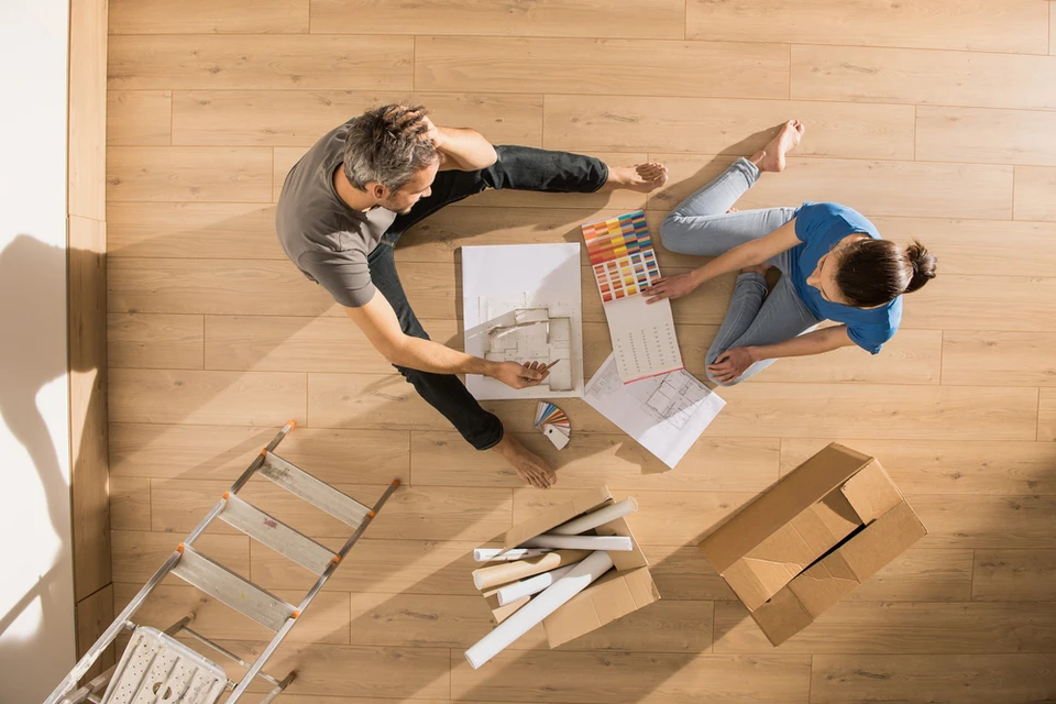 Deux professionnels collaborent sur un projet d'aménagement intérieur, consultant plans architecturaux et nuanciers de couleurs autour d'une table en bois