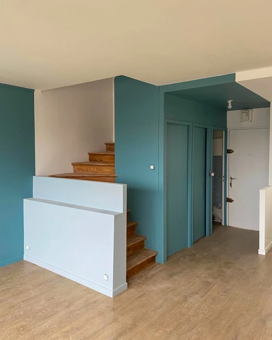 Intérieur d'un appartement rénové, escalier en bois massif avec rampe basse en MDF laqué bleu clair