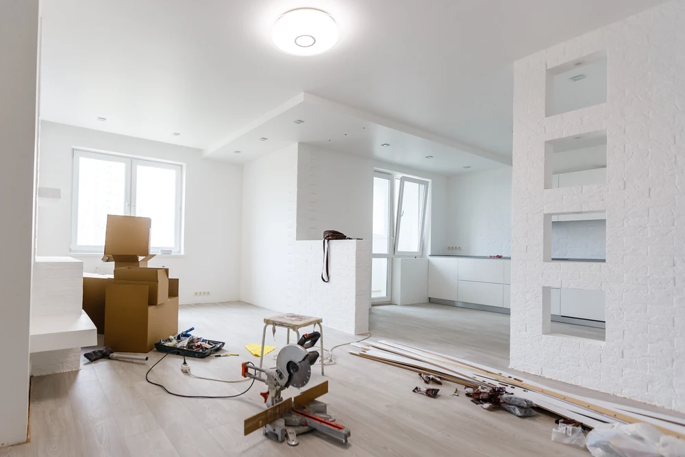 Rénovation intérieure d'un salon en cours avec mur endommagé par l'humidité