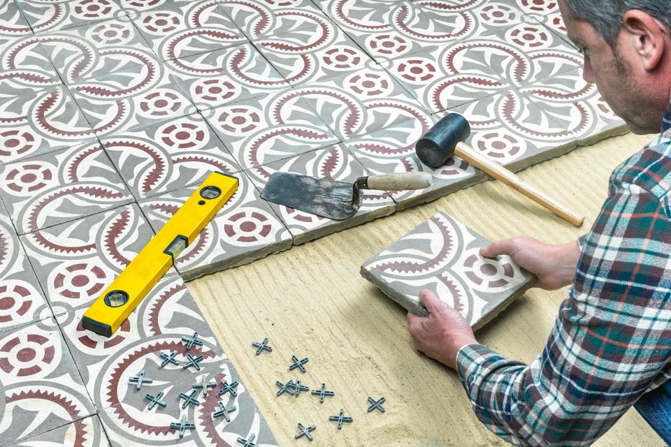 Ouvrier en tenue de travail installe du carrelage mural dans une salle de bains